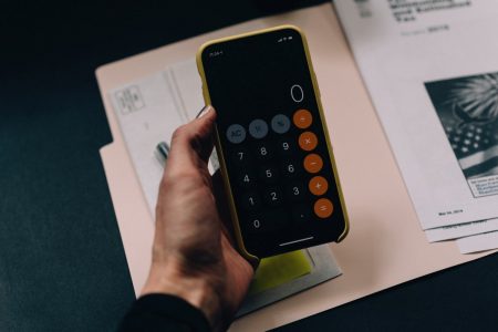 Pessoa segurando uma calculadora em cima de várias contas