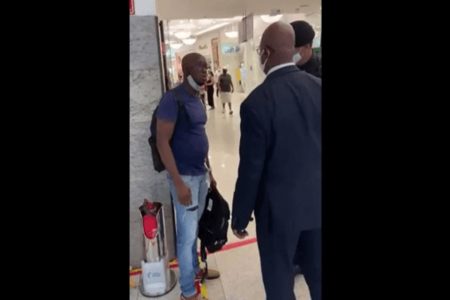 Homem negro sendo coagido por dois seguranças