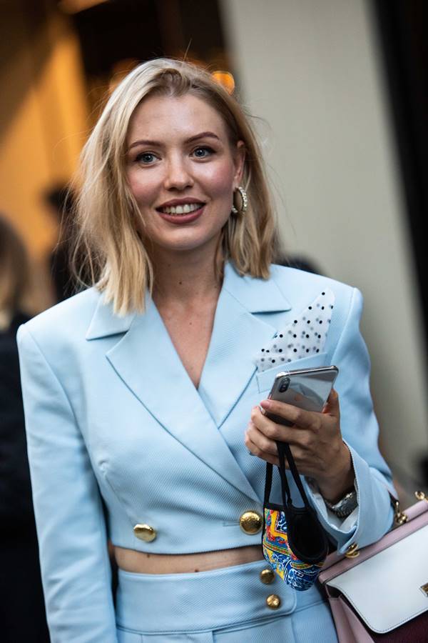 Mulher branca e loira andando na rua com blazer azul