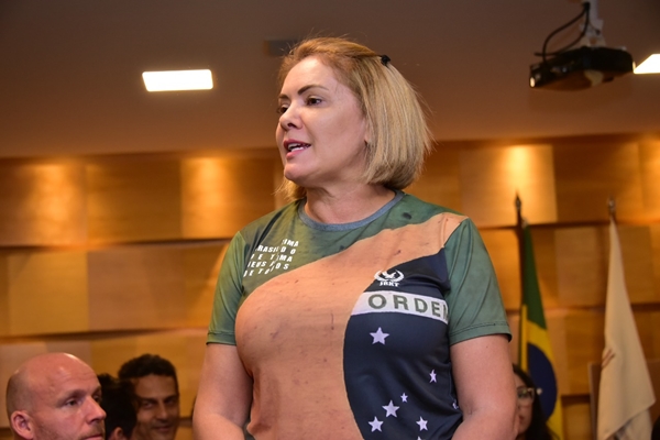 Fotografia colorida de mulher com camiseta que representa bandeira do Brasil
