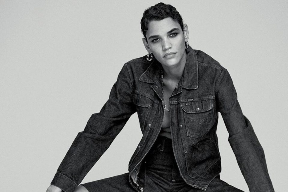 A modelo Kerolyn Soares, uma mulher de pele modera e cabelos curtos pretos, em um retrato preto e branco que foca no seu rosto. Ela usa um brinco delicado de ferragens pratas.