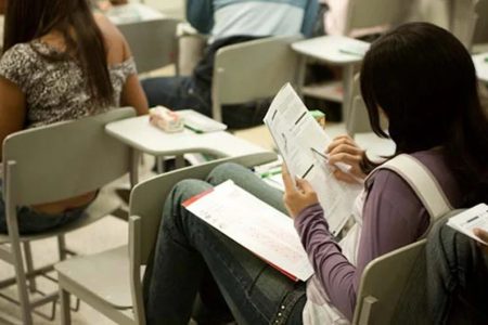 esdutante analisa prova sentada em uma carteira em sala de aula