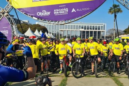 ciclistas perfilados vestidos com roupas amarelas e com prédio ao fundo