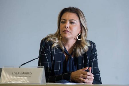 Mulher com terno azul listrado com as mãos apoiadas em mesa