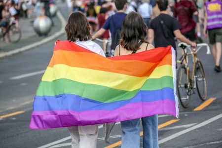 mulheres abraçadas com bandeira lgbtqia+