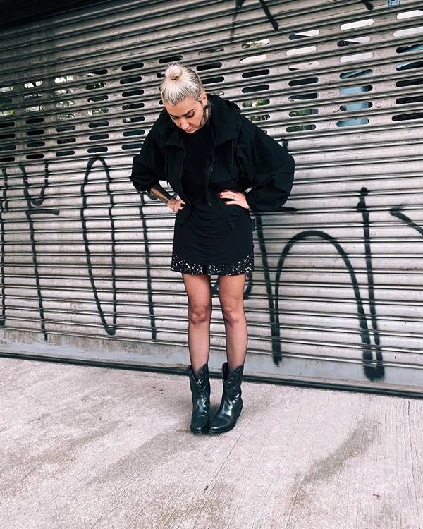 mulher de cabelo preso usa saia prata, bota e meia calça