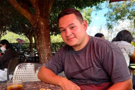 Homem sentado à mesa com um prato de comida à frente