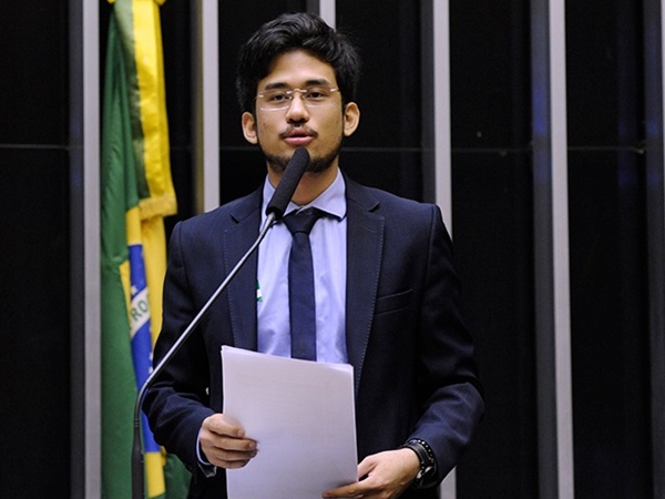 O deputado Kim Kataguiri discursa na tribuna do plenário da Câmara dos Deputados, diante de microfone. Ele segura papel nas mãos - Metrópoles