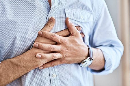 Foto de um homem com camisa azul pressionando o peito - Metrópoles