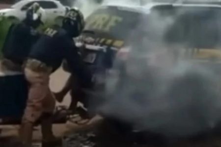 Policiais rodoviarios federais fechando porta de viatura com homem dentro. Há gás saindo do veiculo - Metrópoles