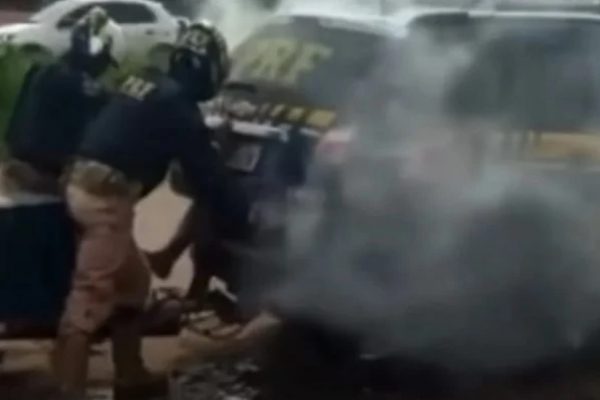 Policiais rodoviarios federais fechando porta de viatura com homem dentro. Há gás saindo do veiculo - Metrópoles