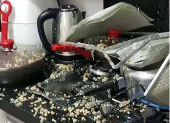 Cozinha doméstica destruída após explosão de panela de pressão. Na foto, o fogão retorcido sujo de feijão - Metrópoles