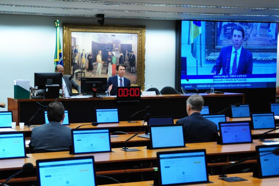 Sala da Comissão de Constituição e Justiça da Câmara dos Deputados com alguns deputados em bancadas frente aos monitores e mesa diretora - Metrópoles