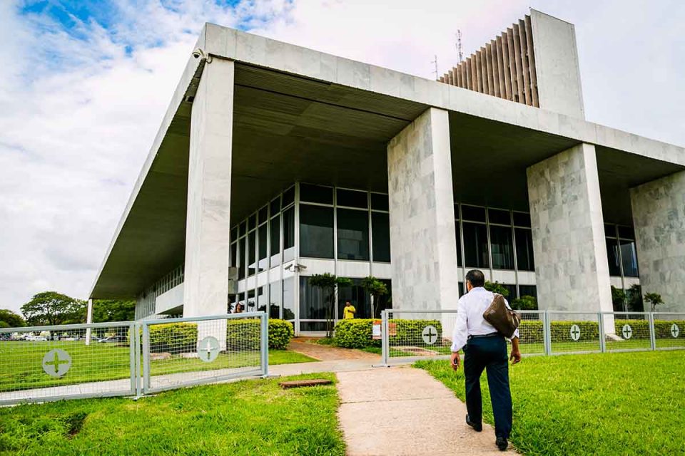 Servidor em direção ao Palácio do Buriti. Homem de roupa social em direção ao um prédio com pilastras brancas