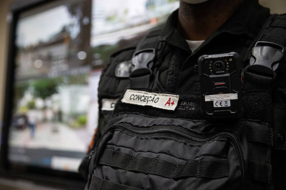 Foto colorida de policial militar com câmera na farda - Metrópoles