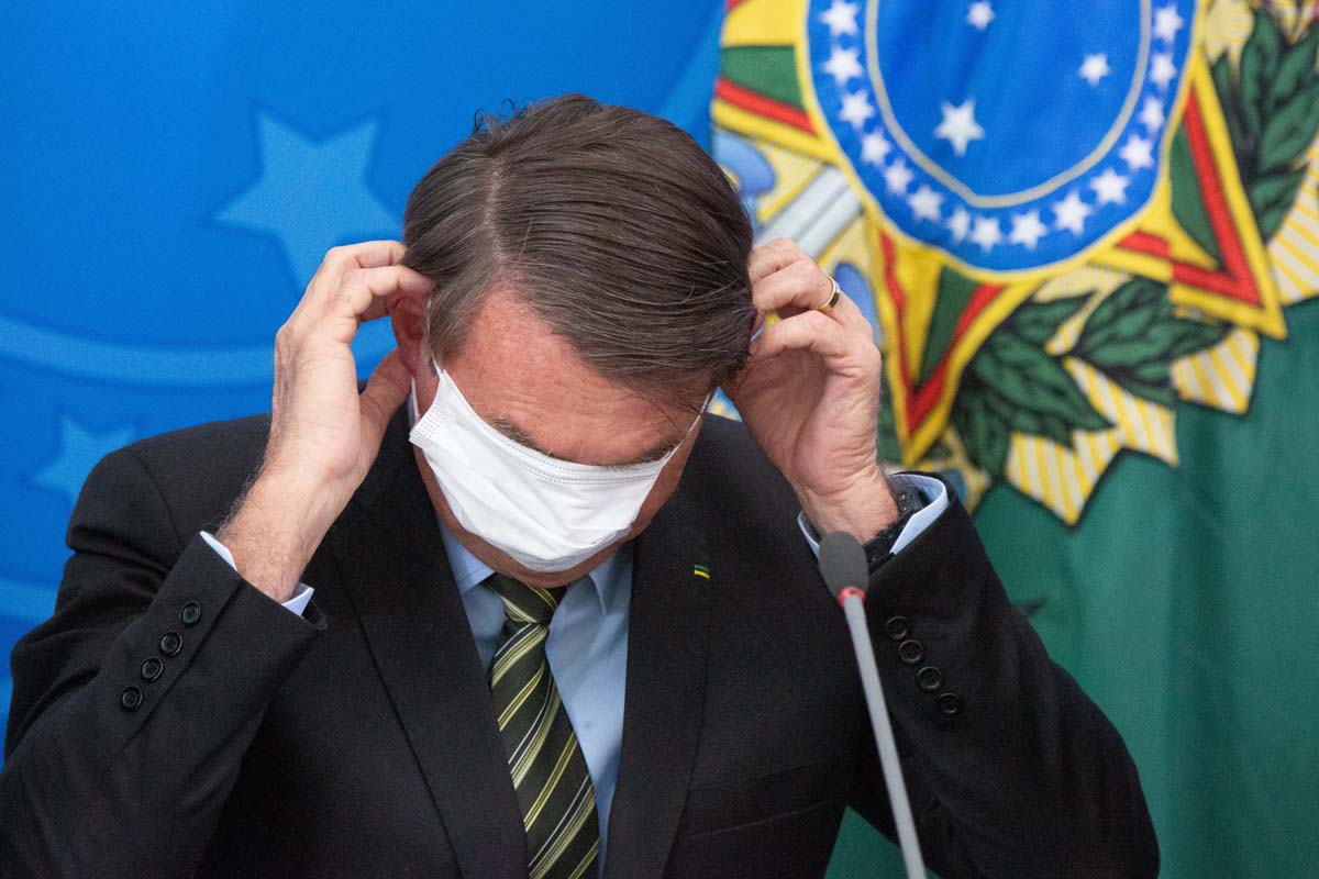 Fotografia colorida mostra Jair Bolsonaro retirando uma máscara de proteção contra a Covid-19 - Metrópoles