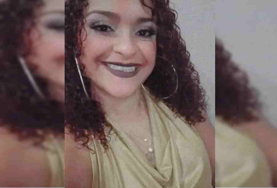 Jovem de cabelos cacheado e batom vermelho sorri para foto