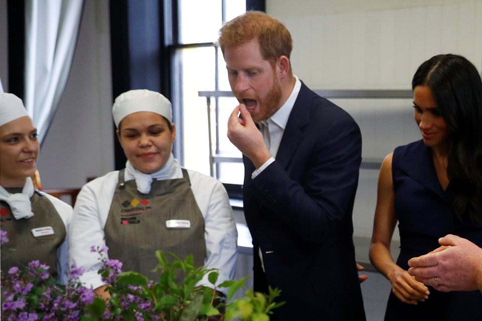 Foto colorida. Príncipe Harry e Meghan Markle comendo