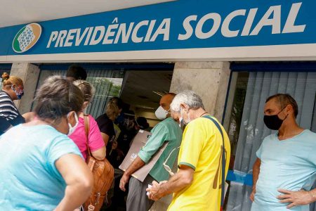 Imagem colorida com fila na frente da sede do INSS em Goiânia