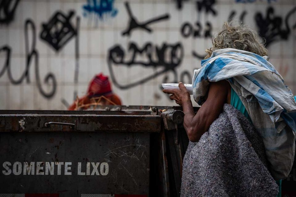 Homem come restos de comida, diretamente do lixo