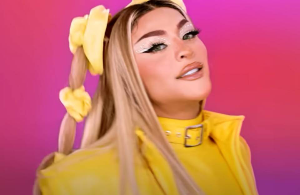 A drag queen e cantora Pabllo Vittar em campanha publicitária #Maisumavoz, realizada pelo mercado livre. Ela olha para a câmera, maquiada e com cabelo loiro longo, sob fundo rosa - Metrópoles