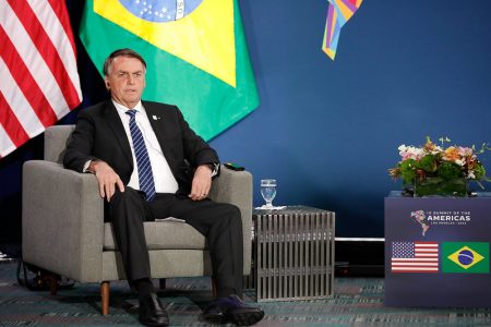 O presidente Bolsonaro sentado em poltrona durante reunião bilateral com o presidente americano Joe Biden na Cúpula das Américas Ao fundo, as bandeiras dos Estados Unidos e Brasil - Metrópoles