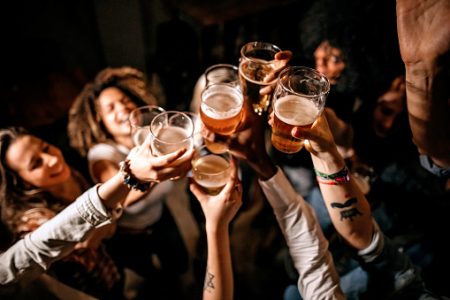 imagem colorida de várias pessoas brindando com cerveja