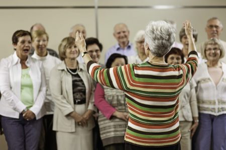 Imagem colorida de pessoas mais velhas cantando em um coral - Metrópoles