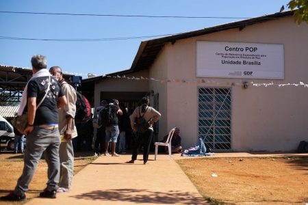 Pessoas caminham em frente a casa