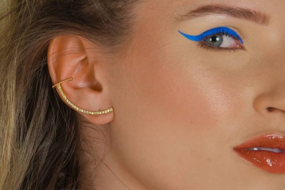 mulher com brinco de ouro e delineado azul