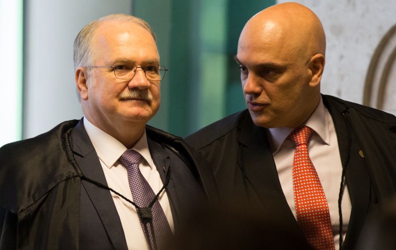 Os ministros do Supremo Tribunal Federal Edson Fachin e Alexandre de Moraes no plenário do tribunal, em pé. Eles usam toga e conversam - Metrópoles