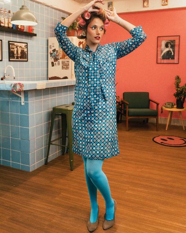 mulher loira com bobs na cabeça usa vestido azul e meias azuis