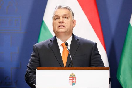 Viktor Orbán, primeiro ministro da Hungria discursa em púlpito com a bandeira do país atrás. Seu discurso com tendências nazistas levou ministra do governo a renunciar - Metrópoles
