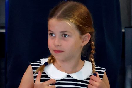 Foto colorida. Menina com tranças e vestido listrado