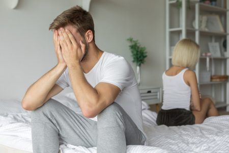 Casal sentado na cama com problemas