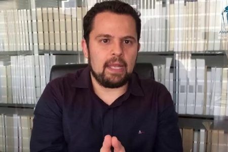 homem falando com biblioteca atrás