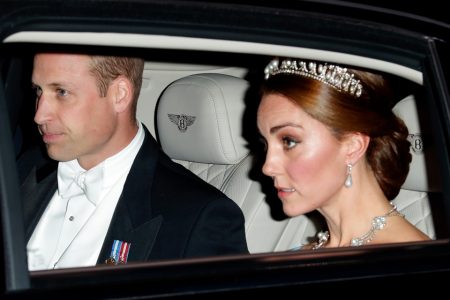 Foto colorida. Homem e mulher dentro de um carro. Ela está com uma tiara e um colar