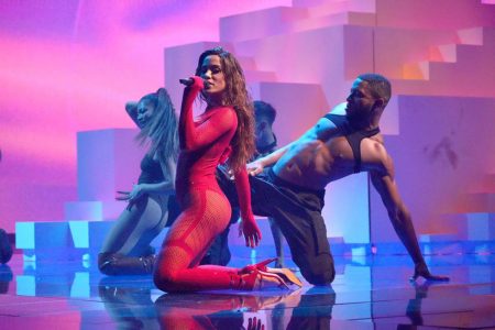 anitta de macacão vermelho colado no corpo de joelhos cantando em palco - metrópoles