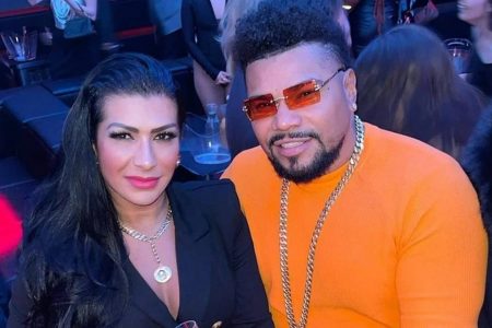 Ellen Cardoso, a Moranguinho, e Naldo Benny. Ela está de batom vermelho e blusa preta. Ele usa óculos com lente vermelha, moletom laranja e cordão prata - Metrópoles