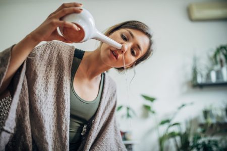 Fotografia mostra mulher fazendo lavagem nasal com um objeto no nariz - Metrópoles