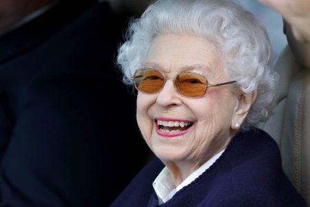 A rainha Elizabeth II com óculos escuros sorri para a fotografia