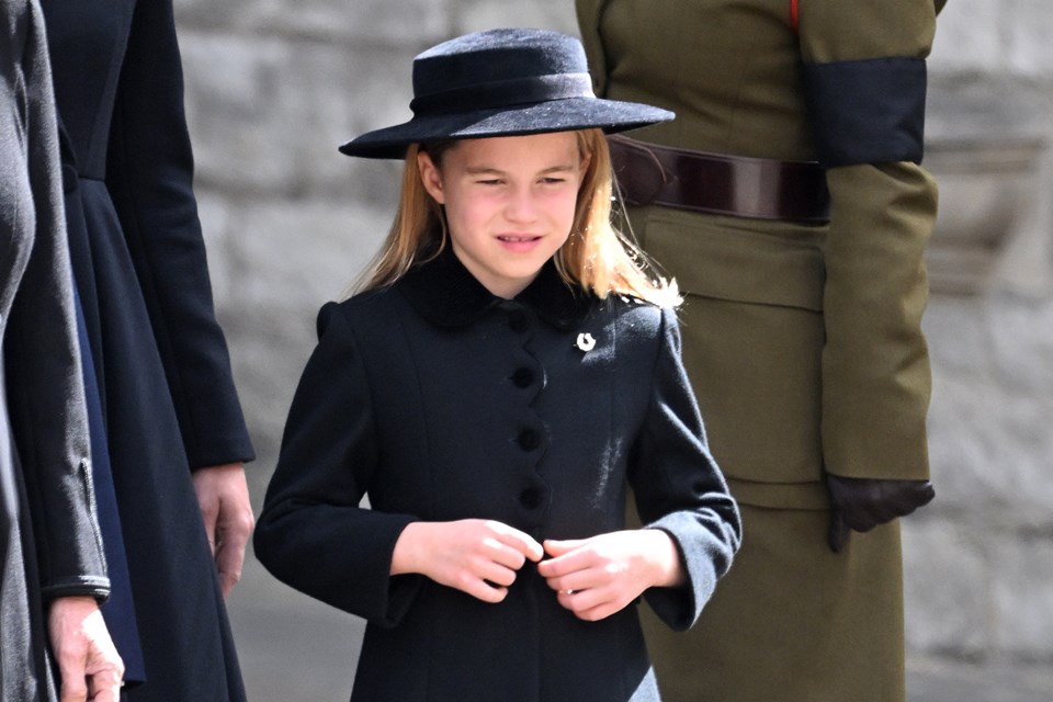 Foto colorida de menina usando vestido preto e chapéus preto. Princesa Charlotte-Metrópoles