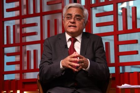 Homem de cabelo branco e terno sentado