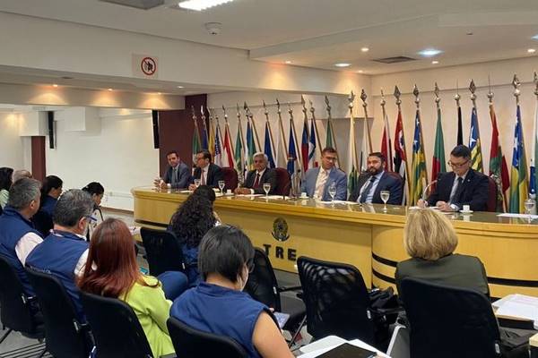 Fotografia colorida de grupo de pessoas acompanhando grupo que discursa