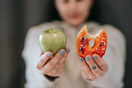 Foro colorida mostra mulher segurando uma maça e um donut