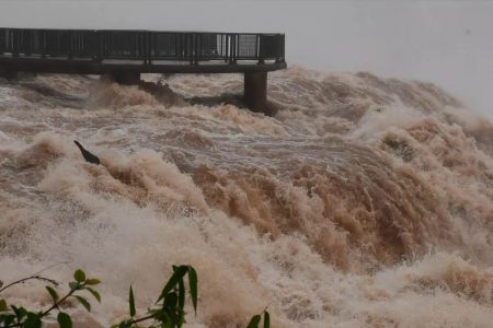 Foto mostra cheia nas Cataratas do Iguaçu, na fronteira entre o Paraná e a Argentina, com fortes ondas de água de coloração amarronzada - Metrópoles