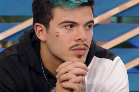 Thomaz Costa, ator e participante do reality "A Fazenda 14", teria supostamente tentando suicídio. Na foto, ele aparece com as mãos entrelaçadas no queixo, olhando para o lado. Usa moletom e tem parte do cabelo pintado de azul - Metrópoles