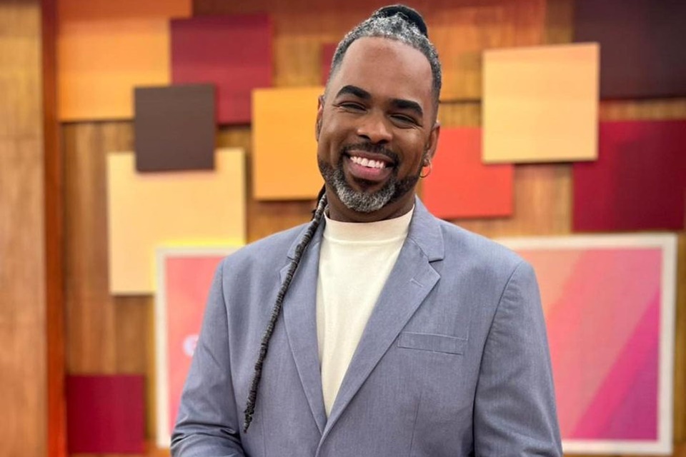 O apresentador do programa "Encontro", da Globo, Manoel Soares. Ele sorri para a câmera usando terno azul e camisa branca com trança de dread escorrendo pelo ombro - Metrópoles