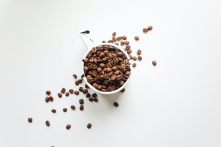 Grãos de café especial dentro de uma xícara branca em fundo branco - Metrópoles