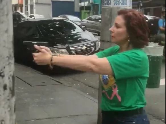 imagem colorida da deputada carla zambelli apontando arma e de camisa verde